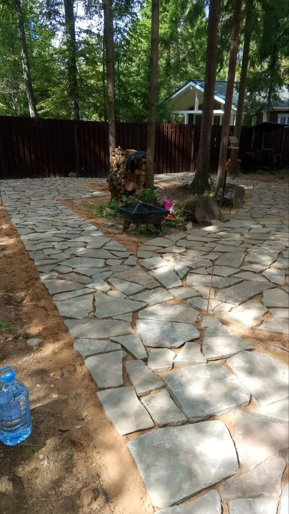 Плитняк уложен на дорожках и площадке между деревьями на участке