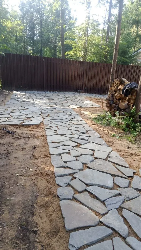 Дорожка и площадка из серого плитняка на участке после укладки